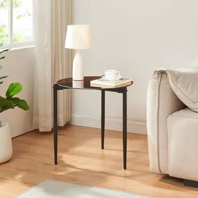 A small round side table with a lamp and books on it, next to a couch.