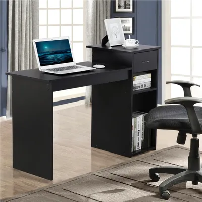 A black desk with a laptop, mouse, picture frame, and books.