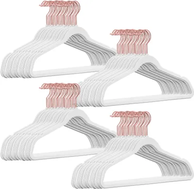 A pile of white velvet hangers with rose gold hooks.