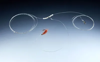 A fishing rig with a fly and beads against a gradient background.