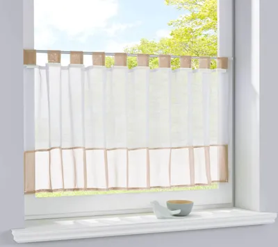 A sheer curtain with a border hangs in a window.