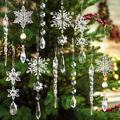 Christmas tree ornaments made of clear crystal in the shape of snowflakes and icicles hanging on a green Christmas tree.