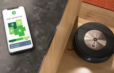 A robot vacuum cleaner is shown next to a smartphone displaying its app interface.