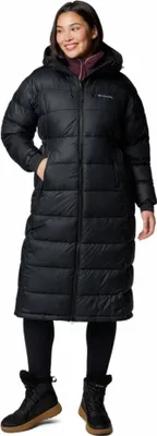 A woman wearing a black puffer coat and boots, standing against a white background.