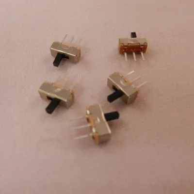 A group of small electronic switches on a textured pink surface.