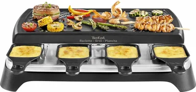 A Tefal raclette grill with food cooking on the top grill and cheese melting in the bottom trays.