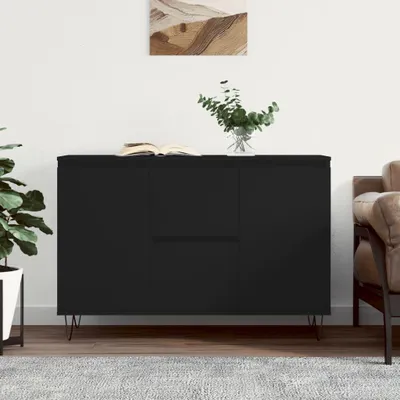 A black sideboard with a book and a vase of plants on top, set against a white wall with a painting.
