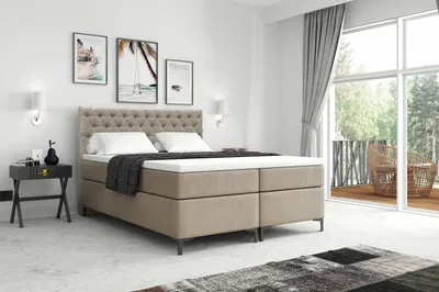 A bedroom scene with a boxspring bed, nightstand, and artwork on the wall.