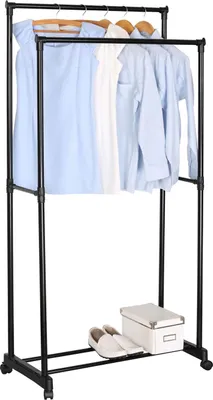 A double-tiered clothing rack with clothes hanging on it, and a pair of slippers and a box on the bottom shelf.