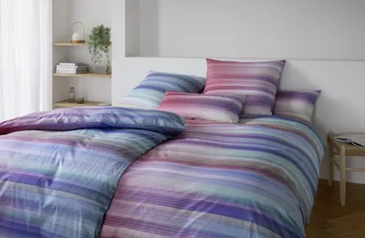 A neatly made bed with striped bedding in a bedroom setting.