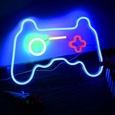 A neon sign shaped like a game controller, glowing in a dark room.