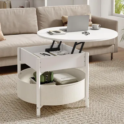A white lift-top coffee table with a fabric basket is shown in a living room setting next to a beige sofa. A laptop, coffee cup, and glasses are on the table.