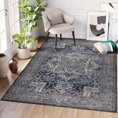 A living room scene with a rug, chair, plants, and artwork.