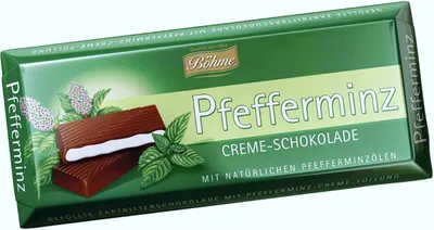 A chocolate bar with mint filling and mint leaves on a white background.