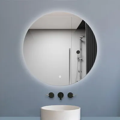 A modern bathroom with a round LED mirror, a sink, and faucets.