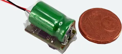 A small electronic component next to a coin for scale.