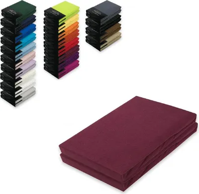 A stack of folded burgundy bed sheets in the foreground, with stacks of colorful folded sheets in the background.