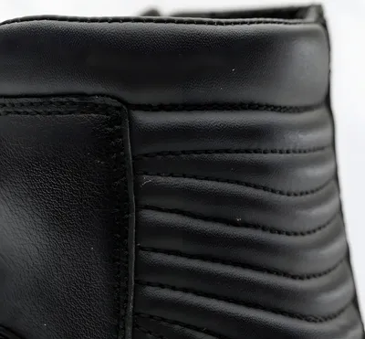 A close-up view of the top section of a black leather boot, showing stitching and quilted detailing.