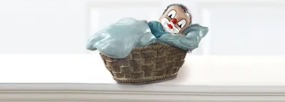 A decorative clown figurine is nestled in a woven basket, covered by a light blue blanket.