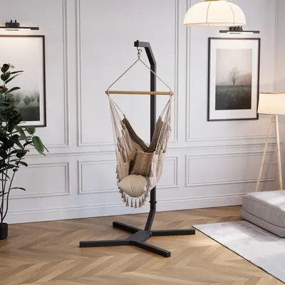 A modern living room with a hanging chair, artwork, and a floor lamp.