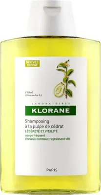 A bottle of Klorane shampoo with a label showing product details and an illustration of a citron fruit.