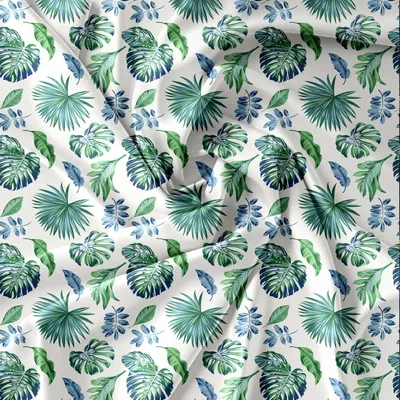 A flat lay of a fabric with a repeating pattern of green and blue tropical leaves.