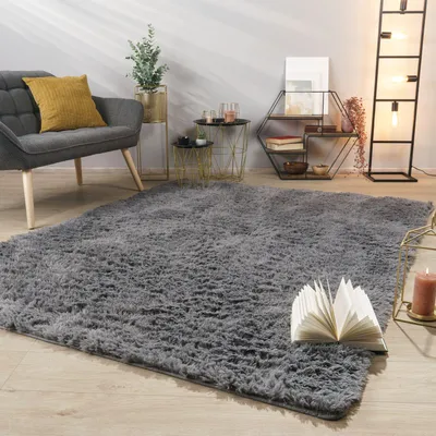 A living room scene with a gray rug, armchair, side tables, and a floor lamp.