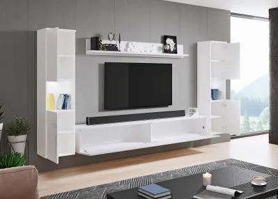 A modern white media console with shelves and cabinets against a gray wall, featuring a large television and a soundbar.