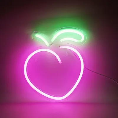 A neon peach-shaped light with green leaves on a pink and dark gray background.
