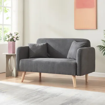 A gray sofa with two pillows sits in a well-lit room with a window and a painting on the wall.