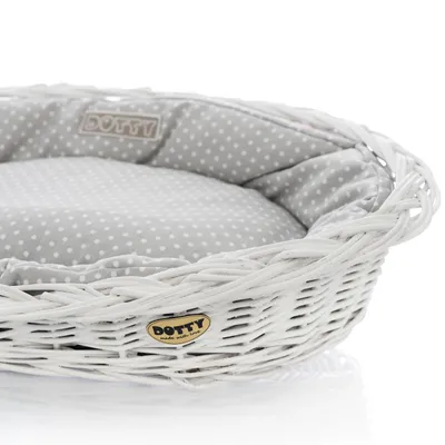 A close-up view of a dog bed made of white wicker with a gray and white polka dot cushion.