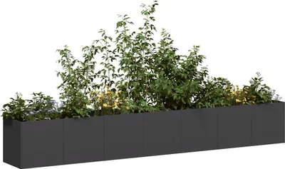 A long, dark planter box filled with various green plants and some yellow flowers, set against a white background.
