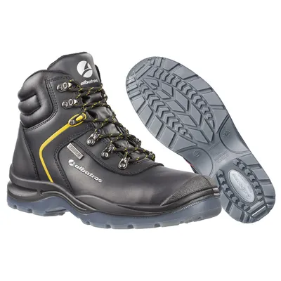 A pair of black and yellow Albatros safety boots and a separate sole are displayed against a white background.