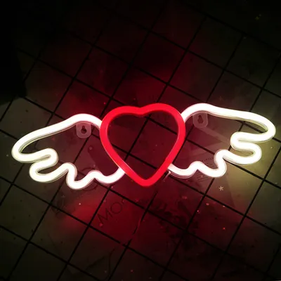 A neon sign shaped like a heart with wings, mounted on a wall.