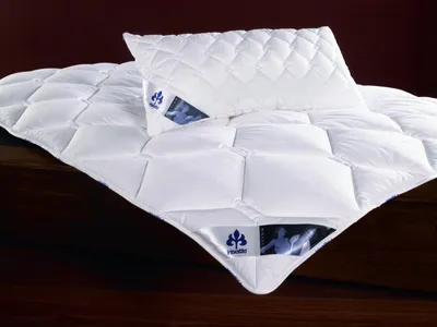 A white quilted duvet and pillow are laid out on a dark wooden surface.
