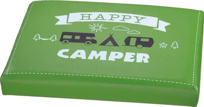 A green cushion with "Happy Camper" text and camping-related graphics.
