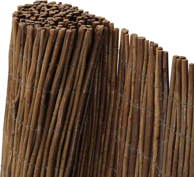 A close-up view of a rolled-up woven fence made of natural reeds or branches, bound together with wire.