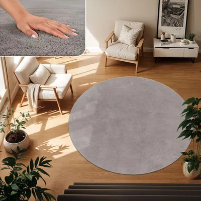 A circular gray rug is placed on a wooden floor in a living room setting, with a chair and plants.