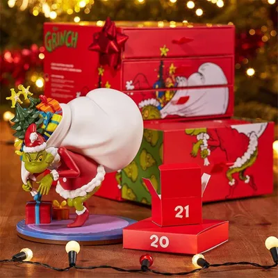 A Grinch-themed advent calendar and figurine set displayed on a wooden surface with festive lights in the background.