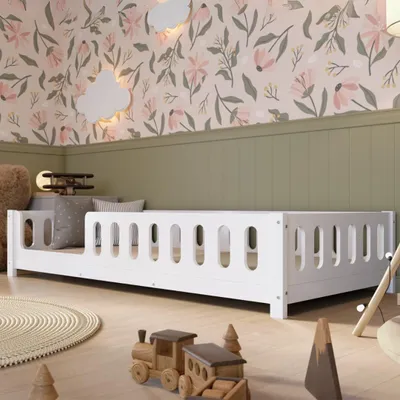 A child's bedroom with a white bed, toys, and floral wallpaper.