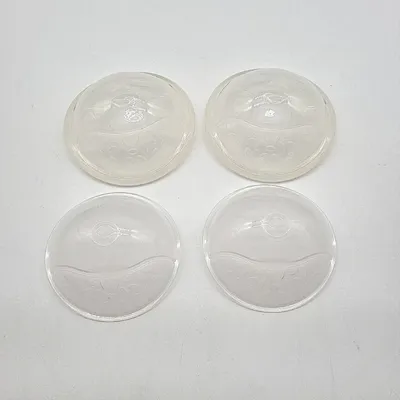 Four clear plastic breast shells are arranged in a two-by-two grid on a white background.