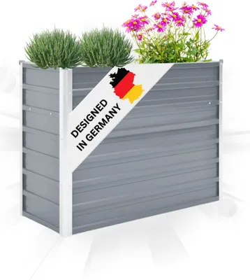 A grey metal raised garden bed filled with green plants and pink flowers, with a diagonal banner showing the German flag and text.