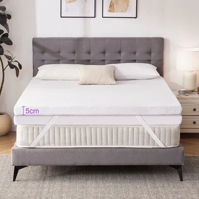 A mattress topper is shown on a bed with a headboard and pillows.