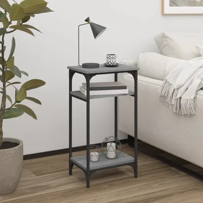 A small side table with two shelves is placed next to a sofa and a large potted plant.
