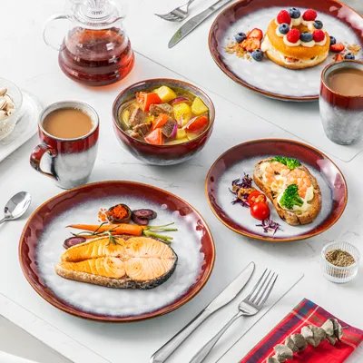 A table setting with a breakfast or brunch spread, featuring plates of food, drinks, and a teapot.