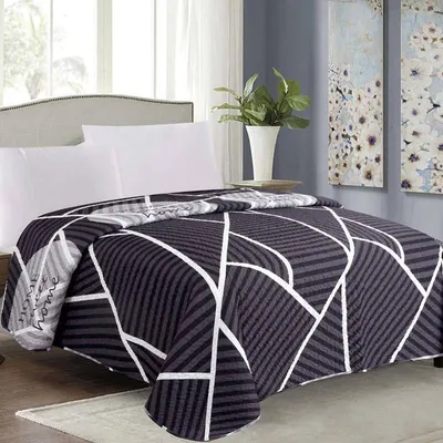 A bed with a blanket and pillows, in a room with artwork on the wall.