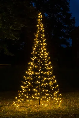 A lit-up Christmas tree decoration in a yard at night.