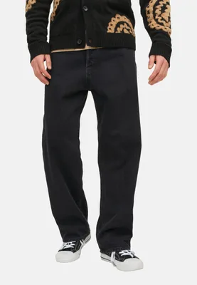 A person wearing black jeans and a black cardigan with a patterned design.