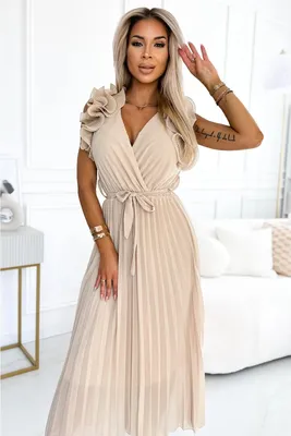 A woman wearing a beige dress in a room.