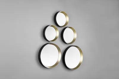A set of five round mirrors with black frames and gold inner rims are arranged in a pyramid shape on a gray wall.